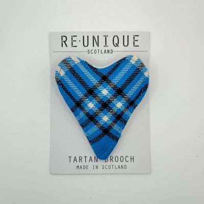 This one-of-a-kind tartan flower brooch, showcasing a captivating blue, black, and light purple Scottish pattern, is presented on a card with the label Reunique Scotland Tartan Brooch - Made in Scotland.