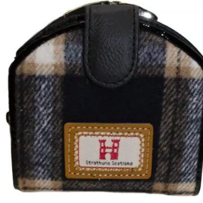 Introducing a chic Black and Camel Tartan Purse accented by a faux leather flap. This fashionable accessory showcases a stitched patch with a vibrant red H and the words Strathurie Scotland on the front. Its elegant black, white, and camel plaid design makes it the perfect statement piece for any wardrobe. Ideal for those searching for timeless style in Scottish-inspired accessories!.