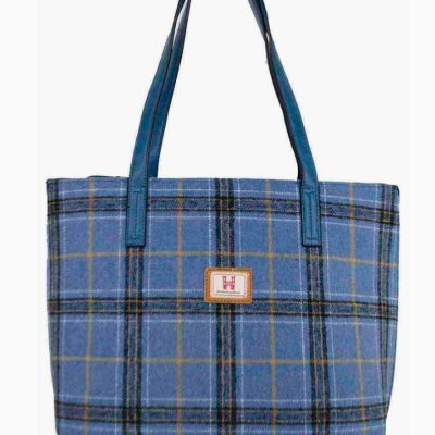The oversized blue shopper handbag boasts a vibrant plaid design with eye-catching green, yellow, and black stripes. This stylish tote features durable blue handles and is adorned with a central patch displaying a bold red H on a crisp white background. Perfect for fashion-forward individuals seeking both functionality and flair, this plaid handbag is sure to make a statement.