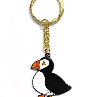The Puffin Keyring is an enchanting accessory perfect for adding a touch of whimsy to your everyday essentials. This delightful keyring features a cartoon puffin design, complete with a striking black and white body, vibrant orange beak, and cheerful feet. Complemented by a stylish gold chain and keyring, this playful yet practical accessory is ideal for keeping your keys organized while showcasing your love for these charming seabirds.