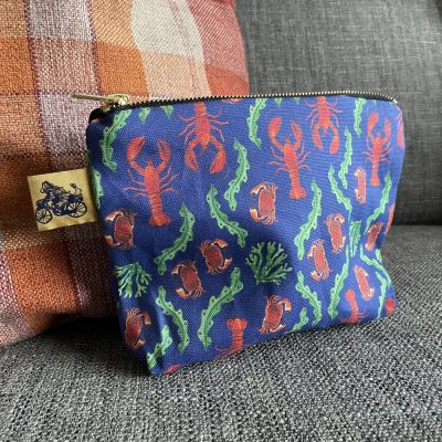 Introducing our Lobster Wash Bag – a stylish and functional accessory for your travel needs. This blue zippered wash bag, adorned with vibrant red lobster designs, lively orange crabs, and elegant green seaweed patterns, adds a splash of coastal charm to your packing essentials. The unique bicycle tag not only enhances its distinctive look but also makes it easy to spot. Perfectly showcased on a modern gray sofa beside a trendy plaid pillow, this wash bag is a must-have for those who appreciate both fashion and functionality while on the go. Upgrade your travel accessories collection with the eye-catching Lobster Wash Bag today!.