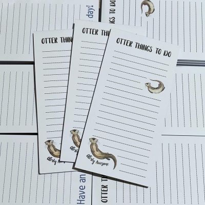 Get organized with our **Otter List Pad Notepads**! This set includes three charming notepads, each featuring **lined pages** and an adorable **otter illustration**. These stylish notepads are perfect for jotting down your daily tasks or shopping lists. The subtle appearance of the word day! in the background adds a fun and whimsical touch to your writing experience. Ideal for otter enthusiasts and those who appreciate cute stationery, these pads are sure to brighten up any workspace!.