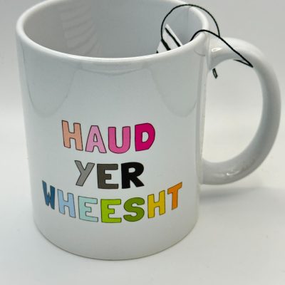 Discover our vibrant white mug featuring the eye-catching phrase HAUD YER WHEESHT in bold, colorful letters. Perfect for tea lovers, this mug comes with a convenient tea bag string hanging gracefully over the handle. Ideal for adding a pop of color and fun to your morning routine.