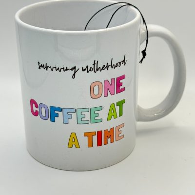 Discover the perfect Surviving Motherhood One Coffee at a Time mug—a colorful and vibrant coffee cup designed for moms who love their caffeine fix. This white tea mug features an eye-catching phrase in lively letters, with a tea bag string elegantly hanging over the rim. Ideal for mothers seeking both function and inspiration, this unique coffee mug stands out beautifully against its plain white backdrop. Perfect for gifting or adding to your own collection!.