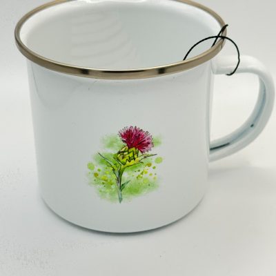 This white enamel mug with a silver rim showcases a vibrant pink flower illustration, complete with detailed green stem and leaves on its side. Perfect for tea enthusiasts, it features a distinctive black teabag string elegantly draped over the rim.