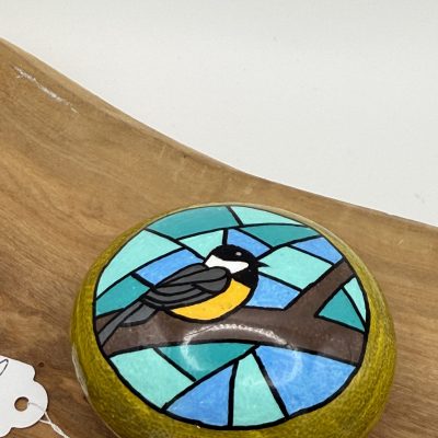 A stunning round decorative box with a stained glass lid showcases a bird perched on a branch against a serene blue background. This unique collectible box is perfect for adding charm to any wooden surface decor.