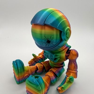 A vibrant 3D-printed robot with rainbow colors sits on a white background, making it an ideal subject for eye-catching visuals. The head boasts a unique black crack-like design on the faceplate, while the limbs and torso showcase stunning gradient hues. Perfect for those seeking colorful robot imagery or creative 3D printing inspiration.