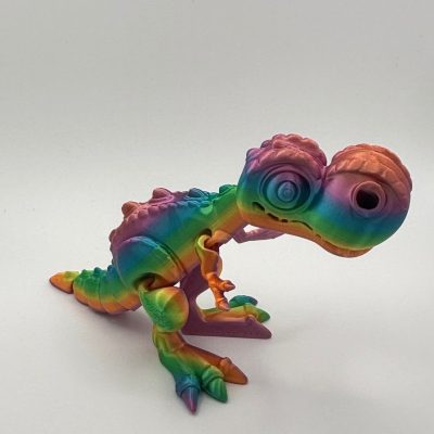 Introducing the 3D Printed Dinosaur Toy: A Rainbow Tie-Dye Delight for Kids! This charming toy features a whimsical design perfect for playful imaginations. With its exaggerated large eyes, bumpy texture, and vibrant rainbow colors, this small dinosaur toy is sure to capture hearts and stand out on any light surface. Perfect as a unique gift or fun decoration, it embodies creativity and charm with every detail.