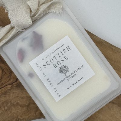 Discover The Library Wax Melts, a premium white wax melt designed to enhance your space. Resting on a rustic wooden surface with textured fabric, this scented wax melt releases an irresistible fragrance featuring elegant rose, pink pepper, and cloves. As it melts, delicate hints of rose petals diffuse beautifully through the air, creating a luxurious and inviting atmosphere. Perfect for those seeking aromatic bliss in their homes!.