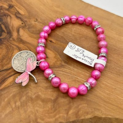 Introducing our Hot Pink Pearl Bracelet with Coin and Dragonfly Charms – a stunning accessory designed to elevate your style. This handcrafted beaded bracelet features vibrant hot pink pearls, elegant silver spacers, a round coin charm, and a delicate pink dragonfly charm for added charm and beauty. Perfect as a statement piece or for everyday wear, the bracelet is displayed on a rustic wooden surface with an attached white price tag. Enhance your jewelry collection with this eye-catching hot pink pearl and charm bracelet – ideal as a unique gift or personal accessory.